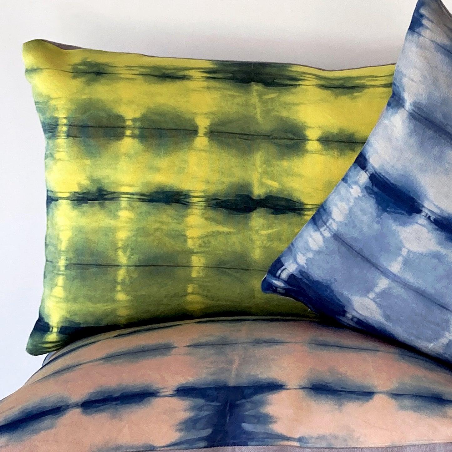Canary yellow, pink and gray silk pillows dyed with indigo, in abstract patterns.