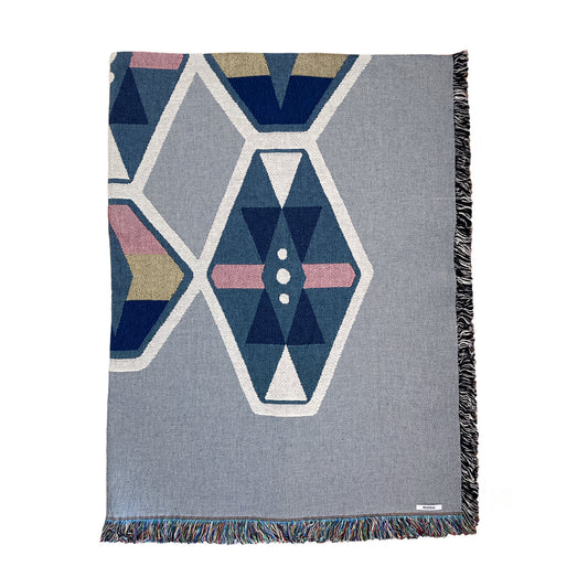 A fog gray and indigo woven throw blanket with a geometric pattern and fringe edge.