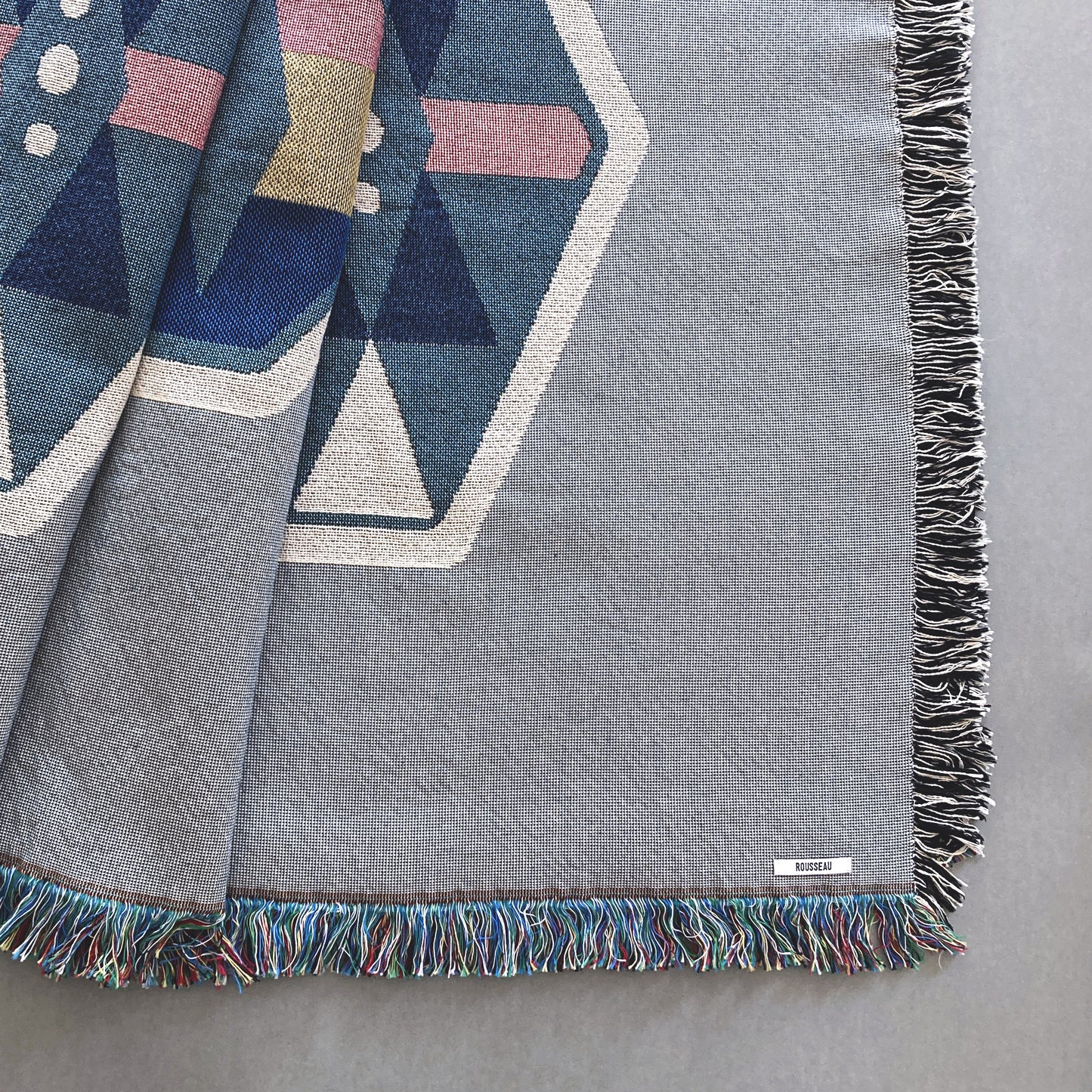 Fog gray geo woven throw with fringe edge. Woven with recycled cotton on a jacquard loom, made in the US. Each throw measures 54 x 72 inches.