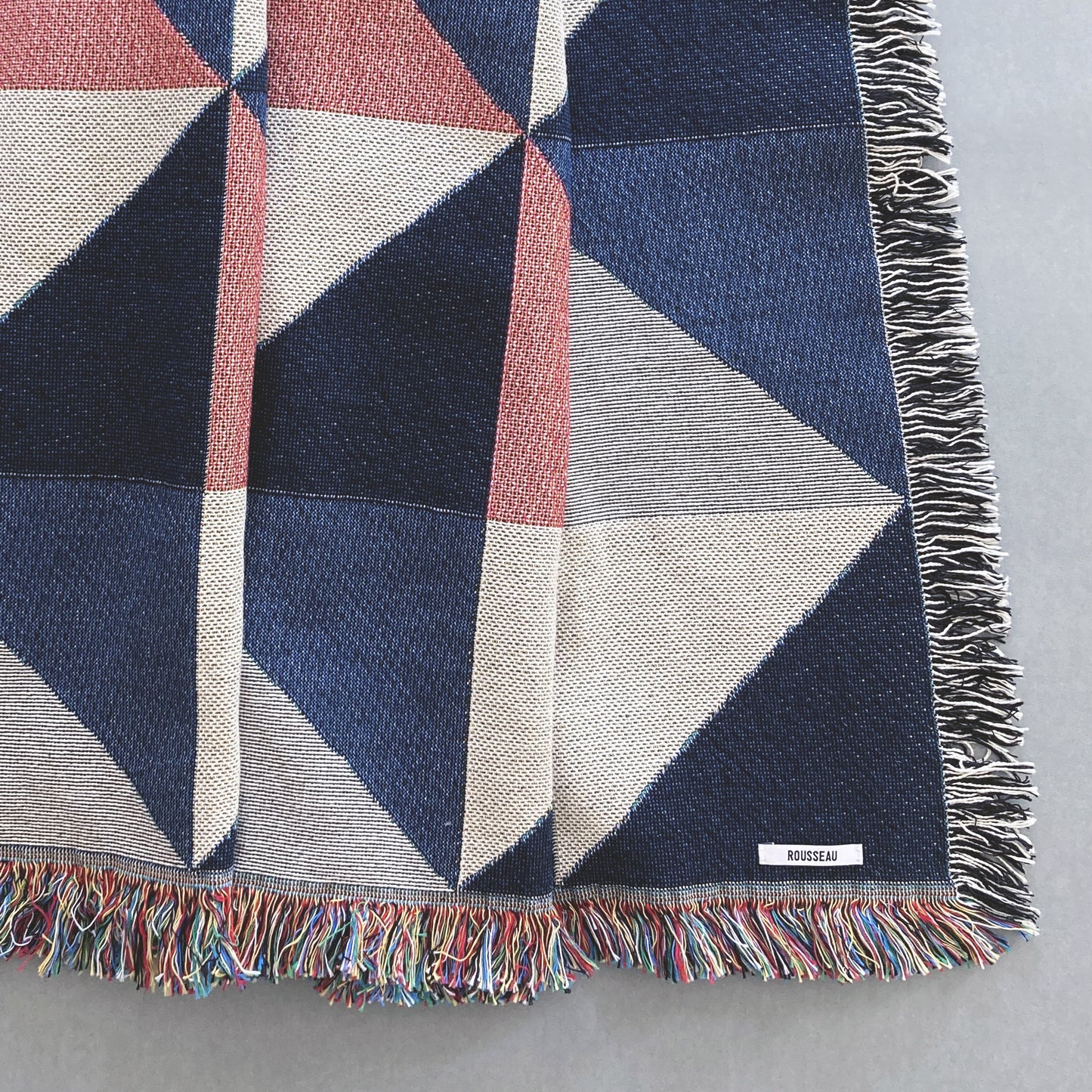 The Sixteen throw in navy, pink, ochre and gray geometric print woven throw with fringe edge. Woven with recycled cotton on a jacquard loom, made in the US. Each throw measures 54 x 72 inches.

This geometric patterned throw is inspired by a painting we created for our New York City studio.
