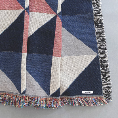 The Sixteen throw in navy, pink, ochre and gray geometric print woven throw with fringe edge. Woven with recycled cotton on a jacquard loom, made in the US. Each throw measures 54 x 72 inches.

This geometric patterned throw is inspired by a painting we created for our New York City studio.