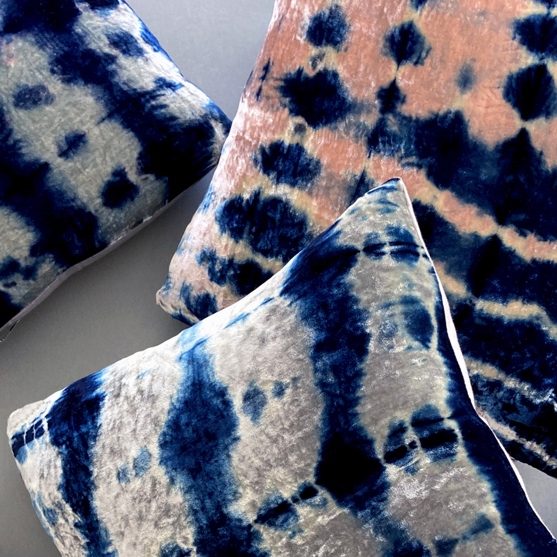 Grouping of silver, pink and indigo velvet pillows in abstract patterns.