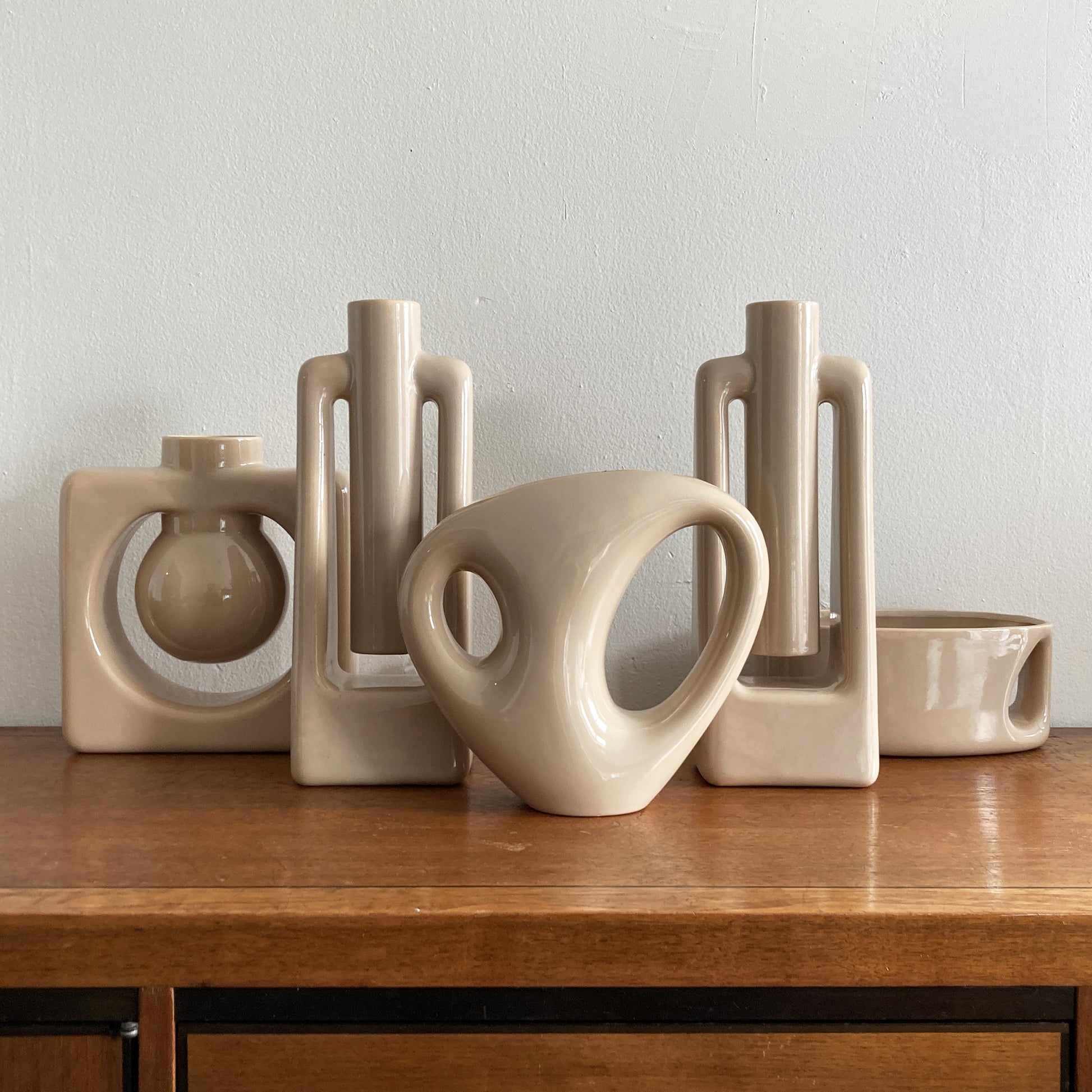 An oblong beige/ecru ceramic vase with a postmodern design, featuring a cut-out on the side.