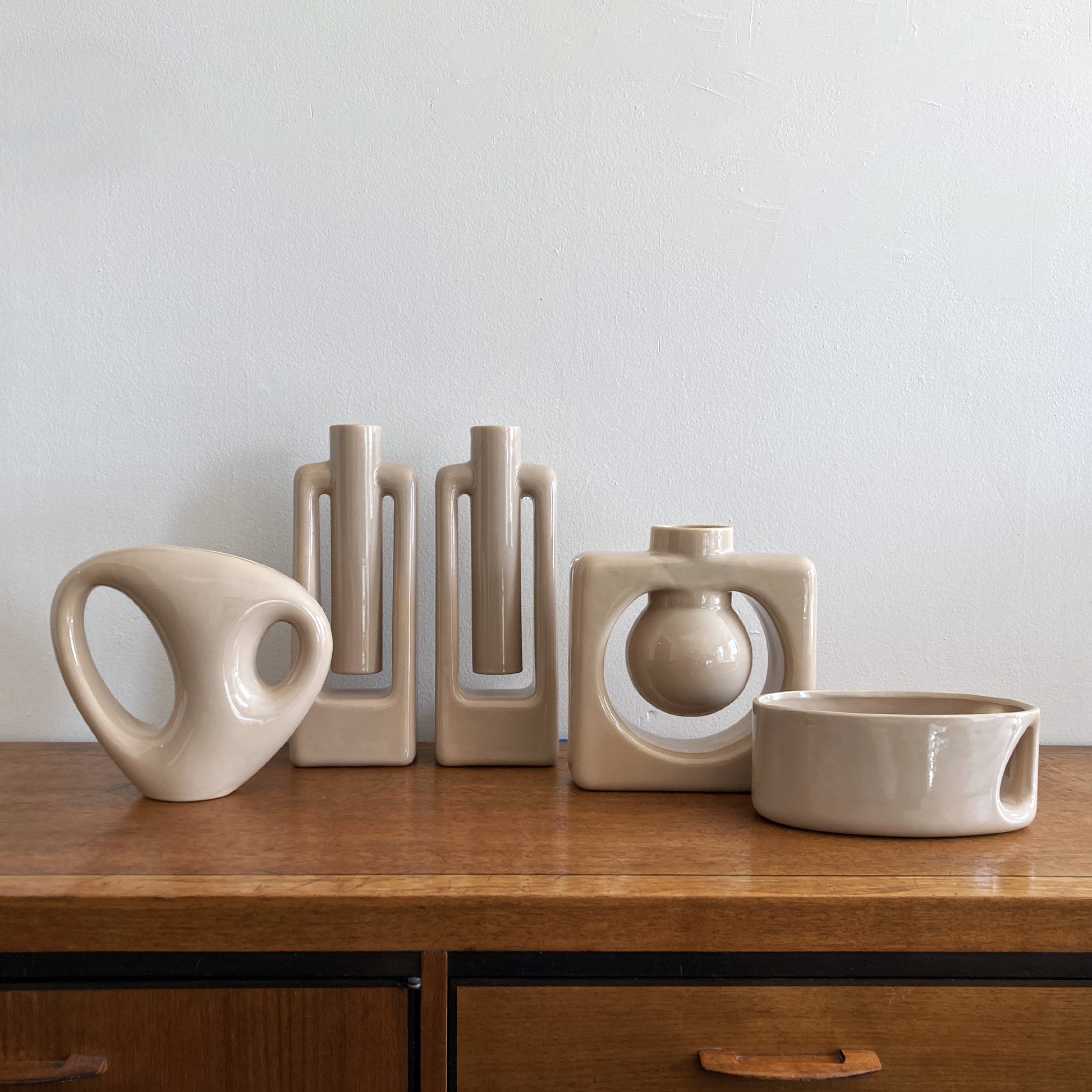 An oblong beige/ecru ceramic vase with a postmodern design, featuring a cut-out on the side.