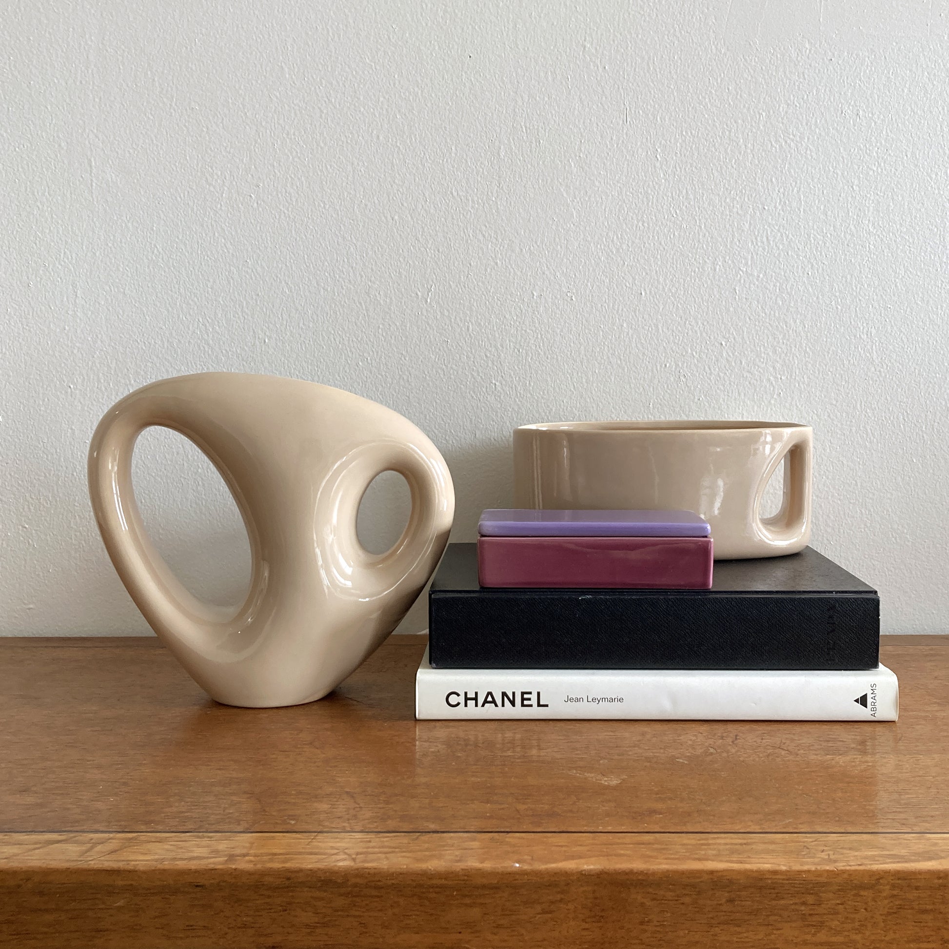 An oblong beige/ecru ceramic vase with a postmodern design, featuring a cut-out on the side.