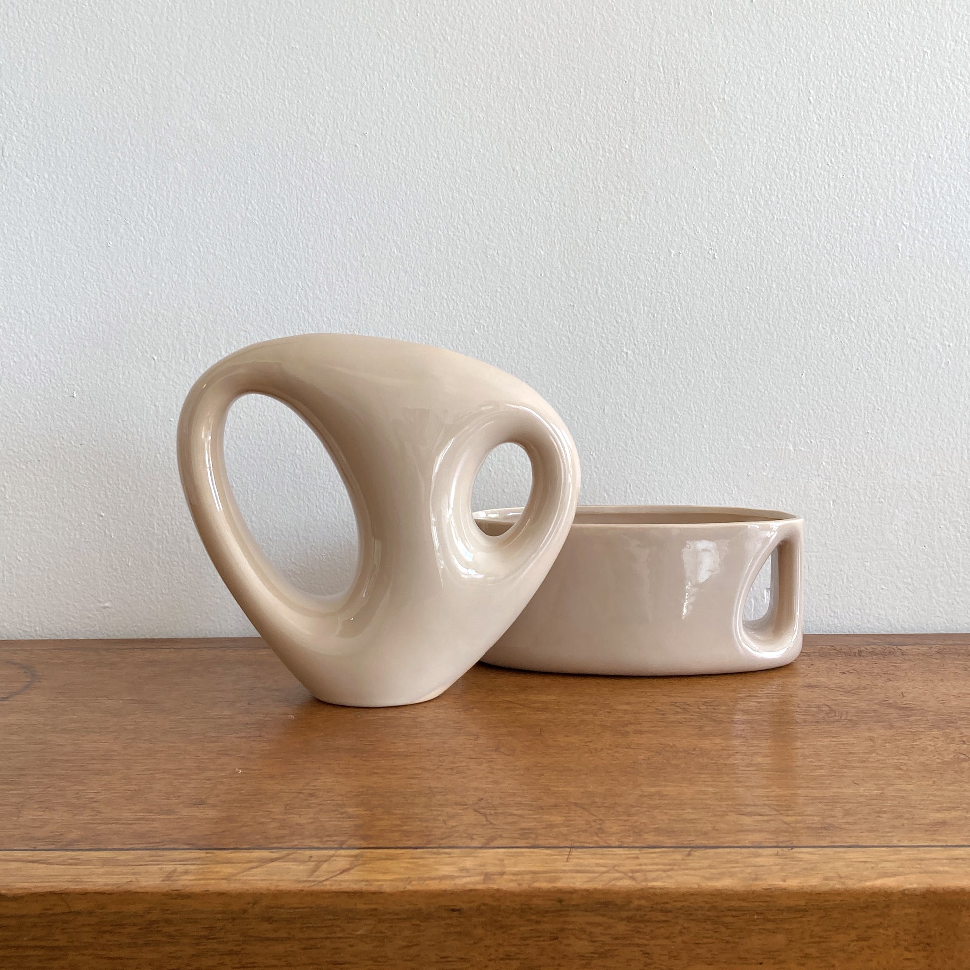 An oblong beige/ecru ceramic vase with a postmodern design, featuring a cut-out on the side.
