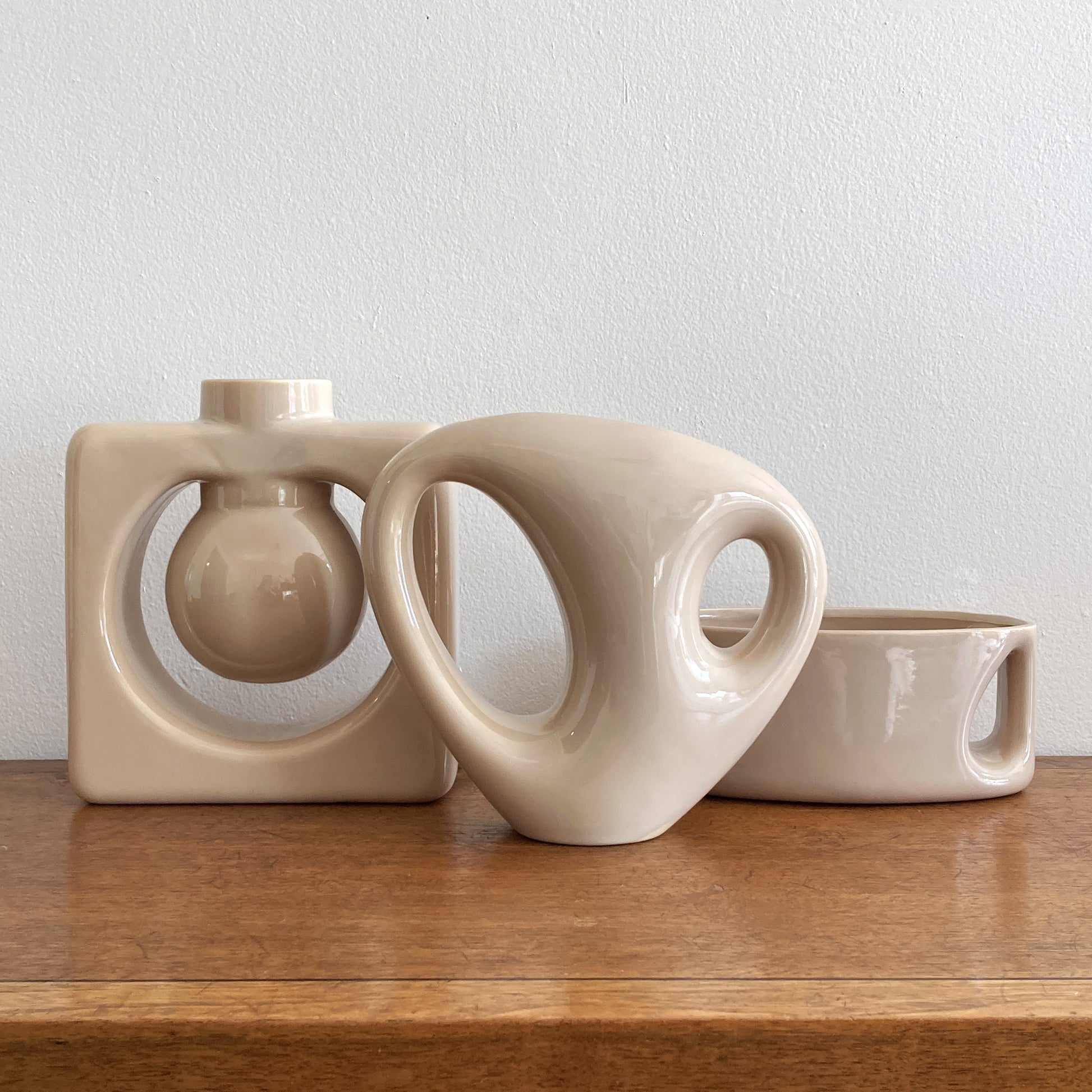 An oblong beige/ecru ceramic vase with a postmodern design, featuring a cut-out on the side.