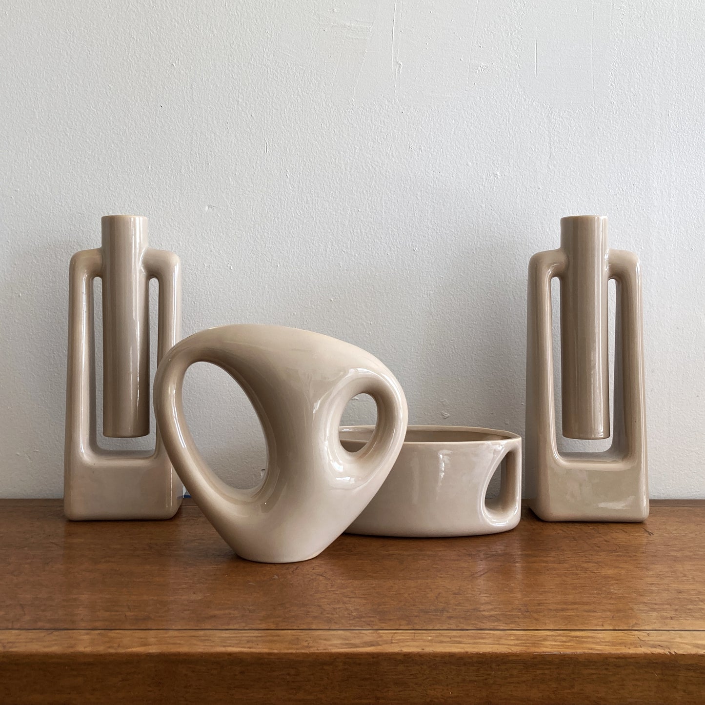 An oblong beige/ecru ceramic vase with a postmodern design, featuring a cut-out on the side.