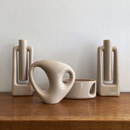 An oblong beige/ecru ceramic vase with a postmodern design, featuring a cut-out on the side.