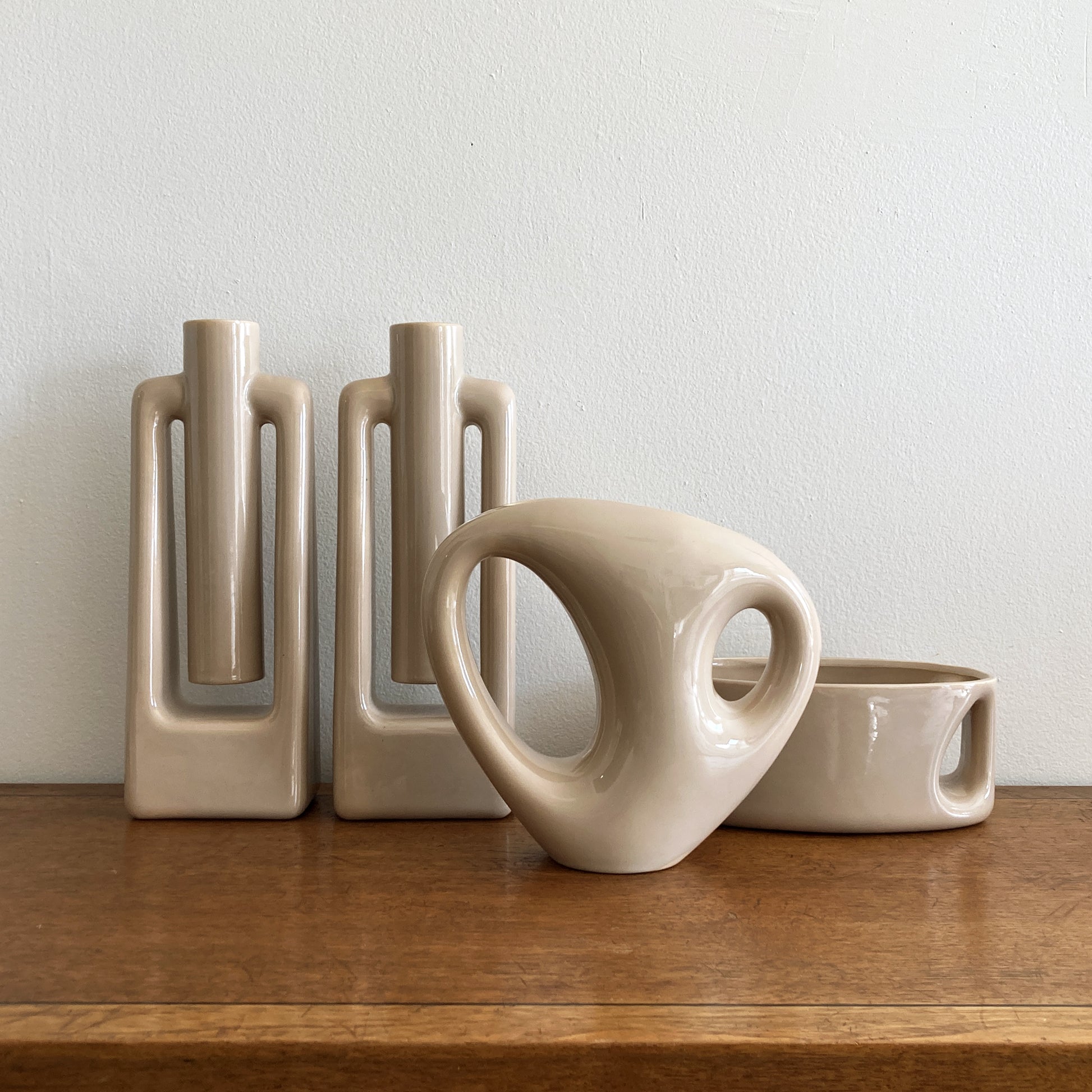 An oblong beige/ecru ceramic vase with a postmodern design, featuring a cut-out on the side.