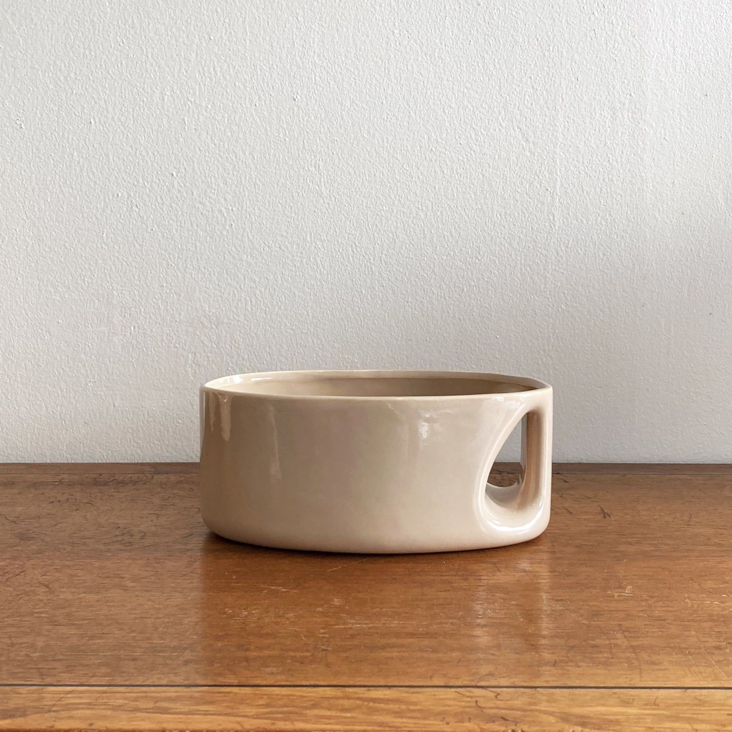 An oblong beige/ecru ceramic vase with a postmodern design, featuring a cut-out on the side.