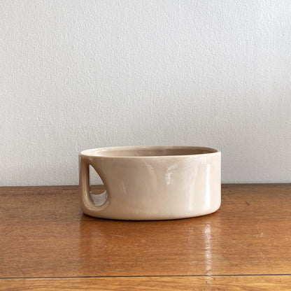 An oblong beige/ecru ceramic vase with a postmodern design, featuring a cut-out on the side.
