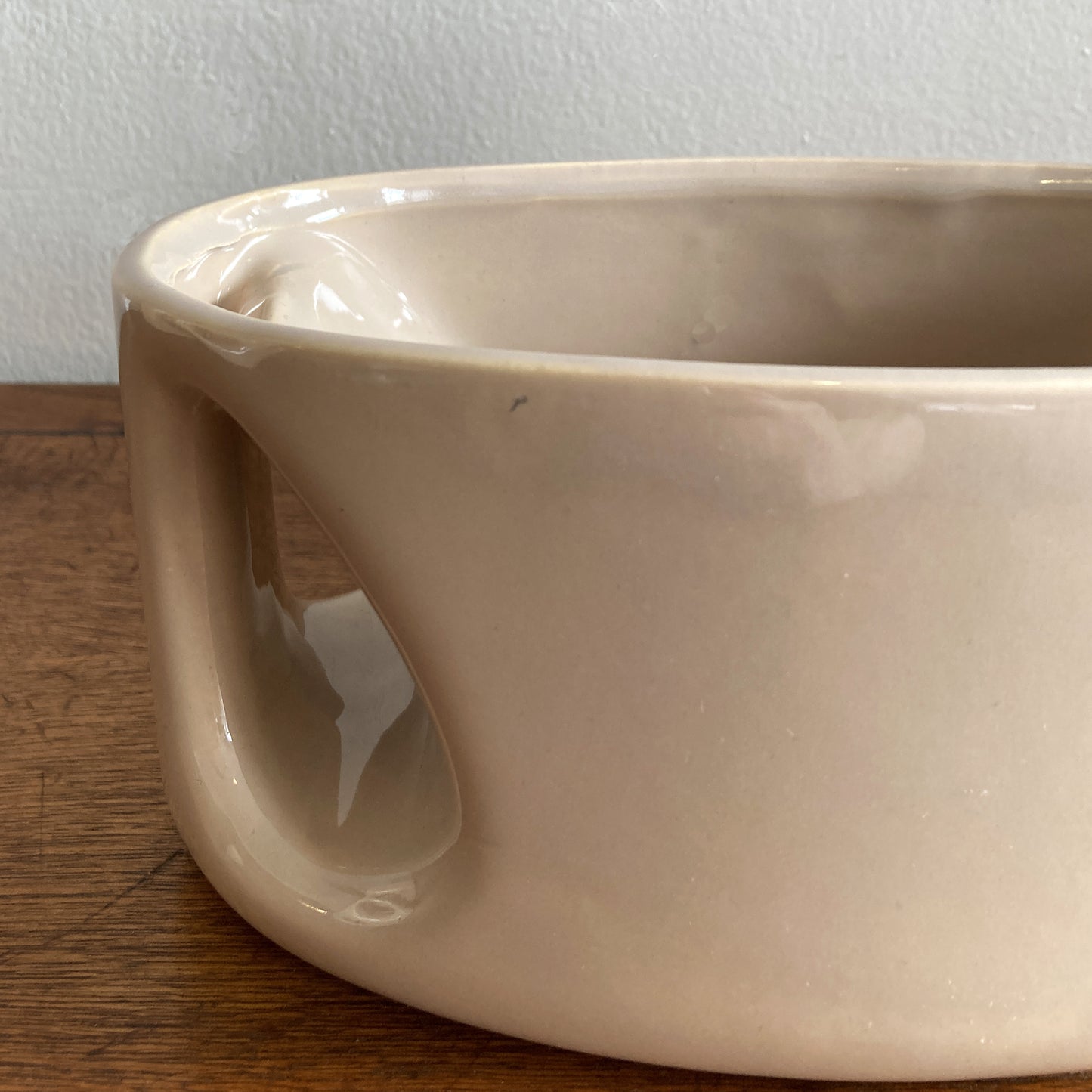 An oblong beige/ecru ceramic vase with a postmodern design, featuring a cut-out on the side.