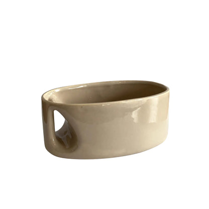 An oblong beige/ecru ceramic vase with a postmodern design, featuring a cut-out on the side.
